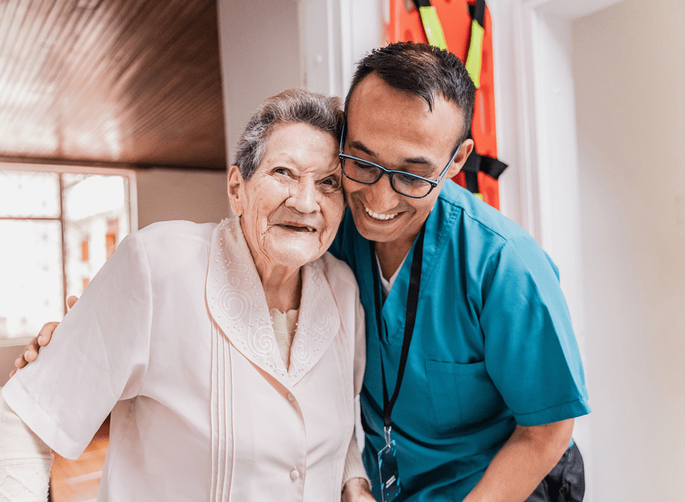 Elderly woman and caregiver smiling together.