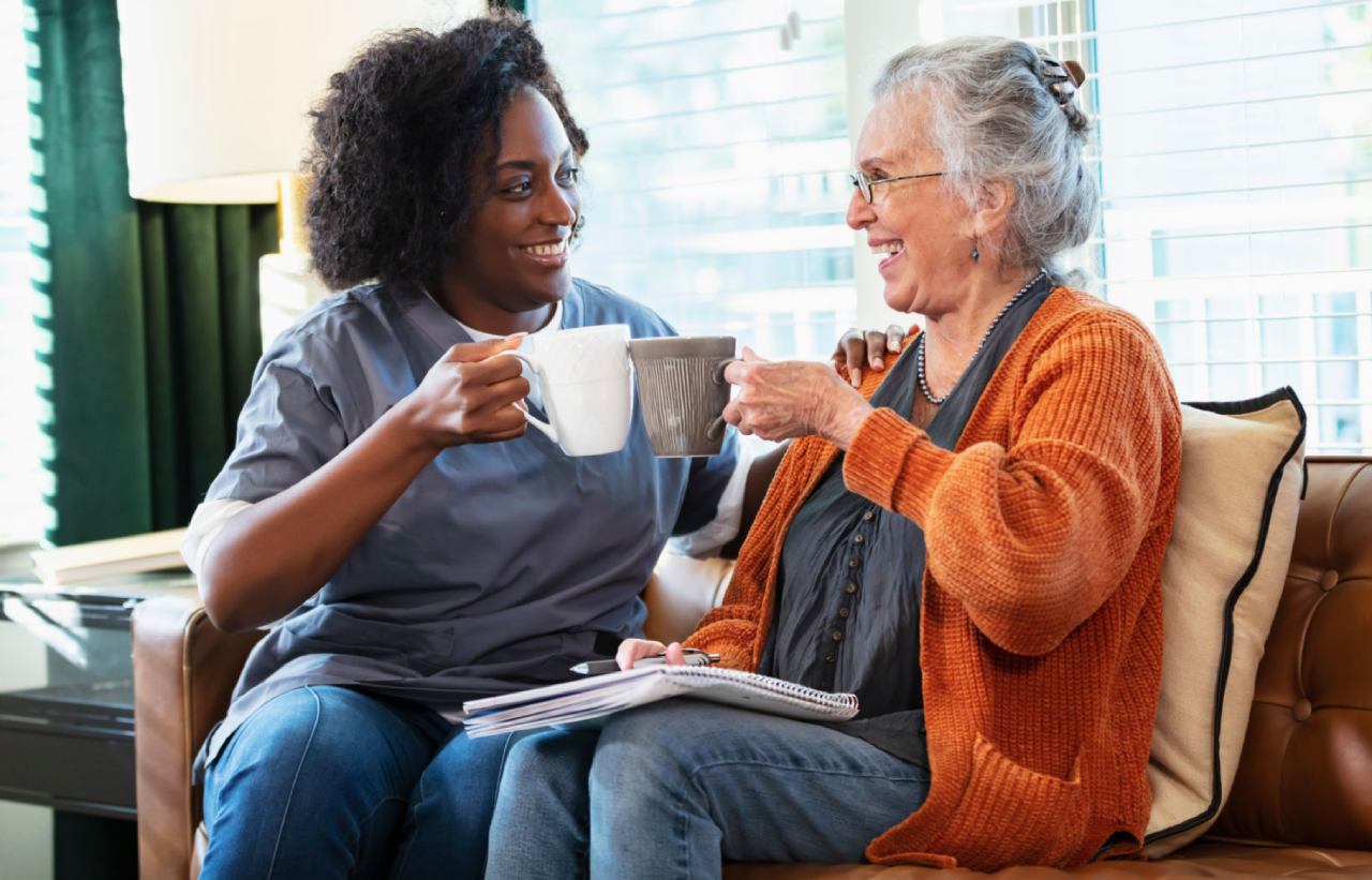 Caregiver and elderly woman sharing coffee together.